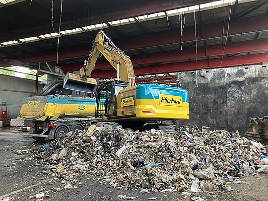Abtransport Brandschutt mit Raupenbagger 40 t mit Greifer auf Rollkipper.
